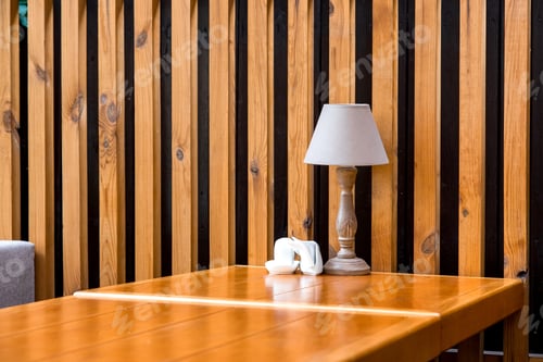 Preview: A Retro Style Wooden Table Lamp Stands On An Table With Napkin By The Decorative Wall Of Brown