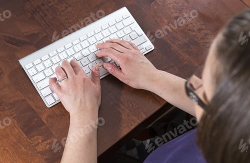 Preview: A Woman Is Writing A Document. The Wireless Keyboard Is On A Wooden Table. The Keyboard Is White.