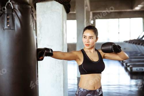 Preview: Young Beautiful Woman Punching A Bag With Boxing Gloves On