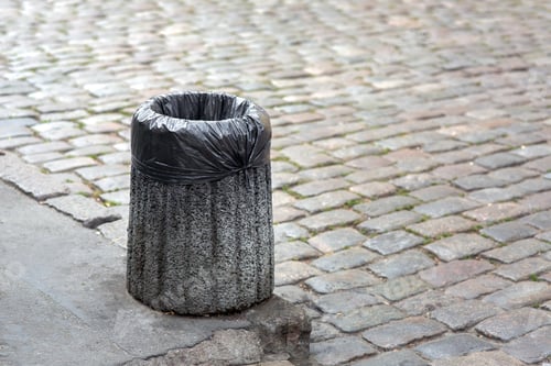 Preview: Trash Bag In A Concrete Bin Mounted On A Pedestrian Pavement Of Paving Stones With Copy Space For