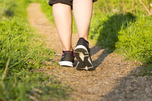Preview: Woman Is Walking The Path With Black Sneakers On Her Feet. She Is Wearing Black Sweater And Black
