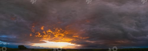 Preview: Cloudy Sunset Evening Sky Above Spring Rapeseed Yellow Fields, Road And Rural Hills Panorama View