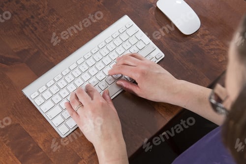 Preview: A Woman Is Writing A Document. The Wireless Keyboard Is On A Wooden Table. The Keyboard Is White.