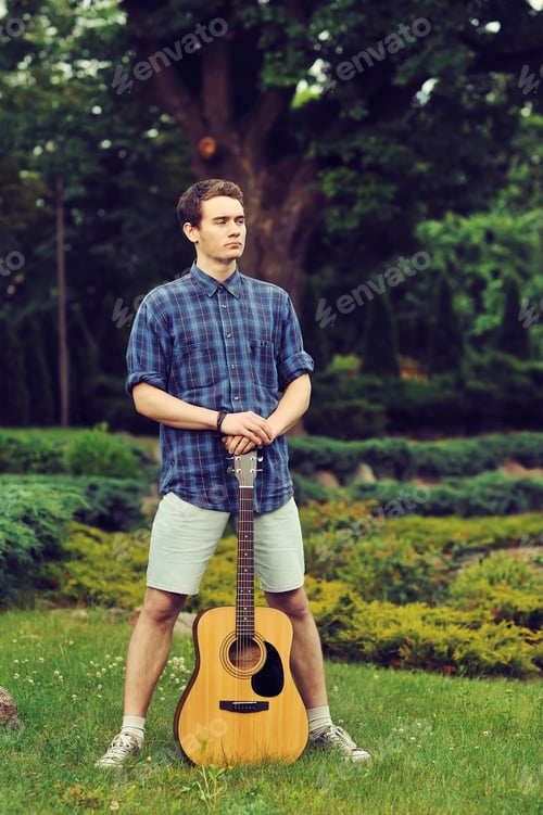 Preview: Young Stylish Hipster Man With Guitar In The Park