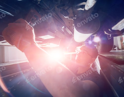 Preview: Car Mechanic Repair Car Suspension Of Lifted Automobile At Repair Service Station. Background