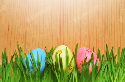 Preview: Painted Easter Eggs In A Green Grass On A Wooden Background. Happy Easter.