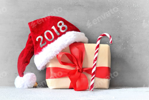 Preview: Box With Christmas Presents And Santa Hat On A Gray Background