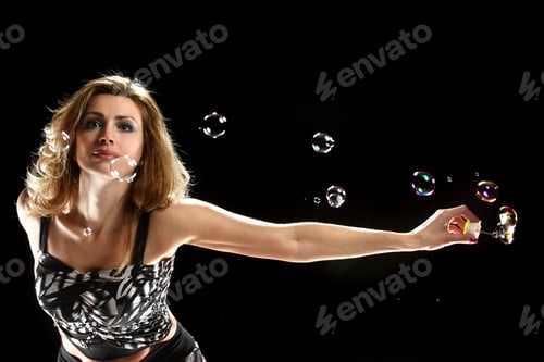 Preview: Young Beautiful Woman Blowing Soap Balls On A Black Background. Vivid Emotions. Dynamics