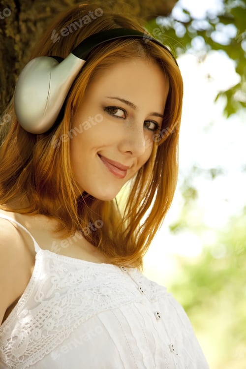 Preview: Beautiful Redhead Girl With Headphones At Garden.
