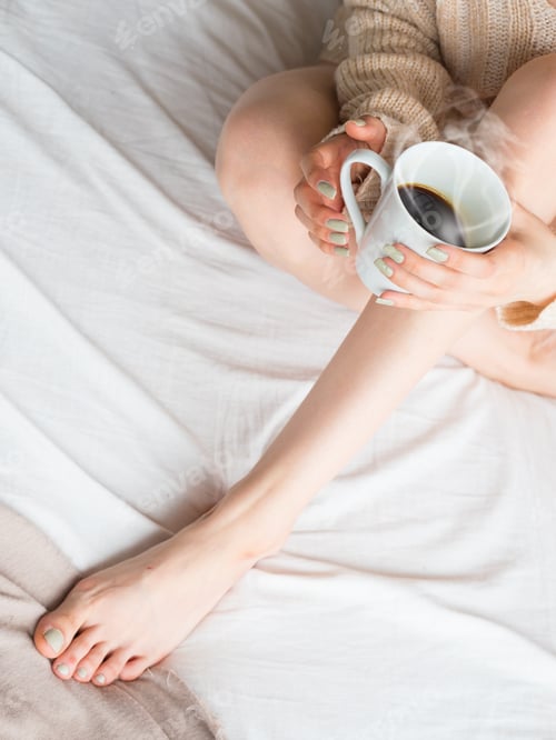 Preview: Young Woman With Sexy Legs Sitting On Bed At Home And Drinks Coffee. Top View