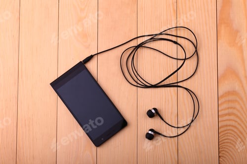 Preview: Mobile Phone With Pair Of Earphone On Wooden Table