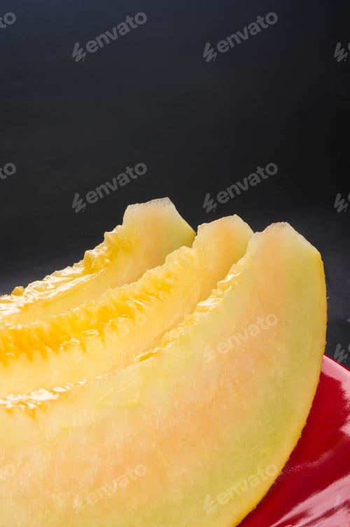 Preview: Slices Of Ripe Juicy Melon In Red Plate On Black Background