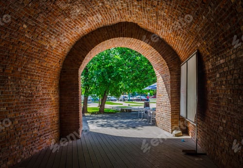Preview: A Brick Arch With A Green Tree Behind It.