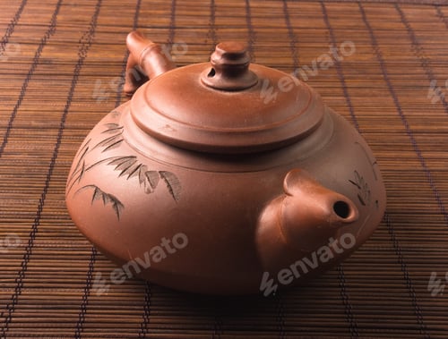 Preview: Brown Chinese Teapot Of Yixing Clay With Traditional Ornament On Bamboo Mat