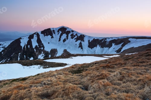 Preview: The Meadow With The Rocks And Yellow Grass. Landscape Of High Peaks Of Mountains Covered With Snow