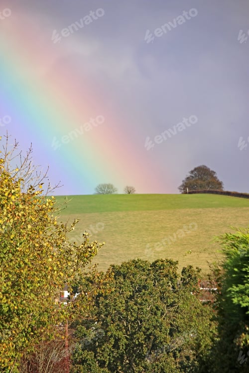 Rural Landscape with Rainbow Above a Green Hill