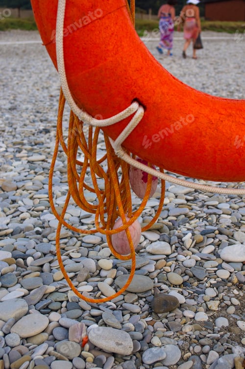Preview: Orange Lifebuoy On A Pebbly Sea Beach, Sunset