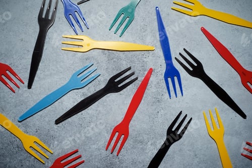 Preview: Multicolored Plastic Cutlery On A Stone Table.