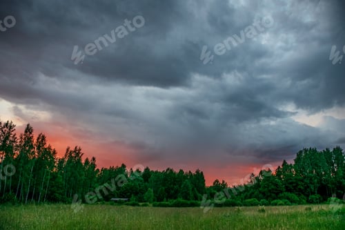Preview: Contrast Rain Storm Clouds Over Green Meadow And Some Trees In Summer. Blue Sky Before The Rain