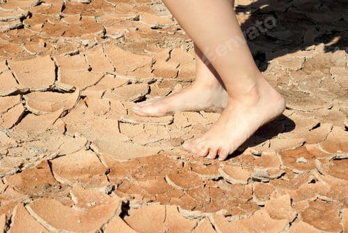 Preview: Bare Feet Of Woman On A Dry Cracked Clay Surface In The Desert
