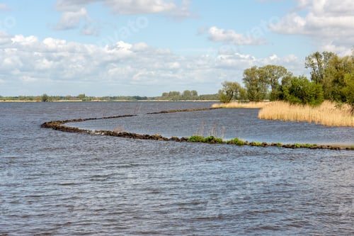 Preview: Curved Dam Of Basalt Boulders In The Water Of A Dutch River. The Photo Was Taken On A Sunny Day In
