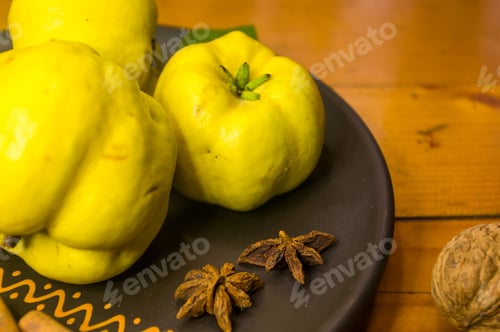 Preview: Large Yellow Quince Fruits On A Ceramic Plate, With Anise, Cinnamon, And Walnuts