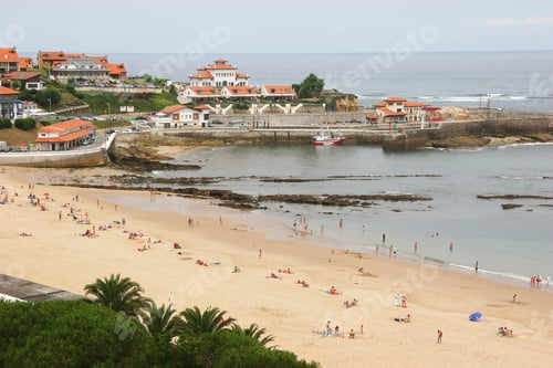 Preview: Seascape With People Having Vacation On The Beach And Coastal Village And Harbor In The Background