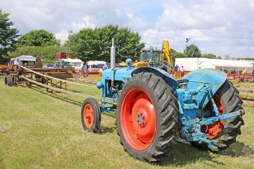 Preview: Blue Tractor Pulling Equipment on Grassy Field
