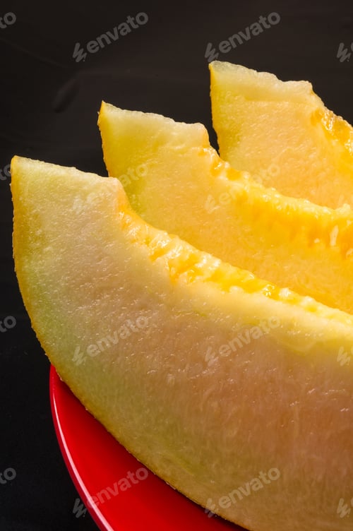 Preview: Slices Of Ripe Juicy Melon In Red Plate On Black Background