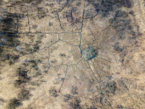 Preview: Aerial View Of Small Country River Bed Wavy In Spring Time In Countryside With Dry Grass And Some