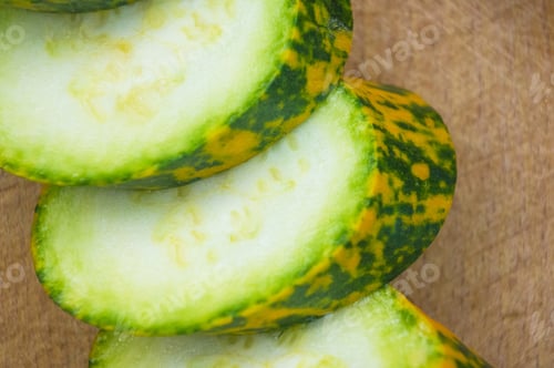 Preview: Slices Unusual Green-Orange Zucchini And Red Chilly On An Old Wooden Background