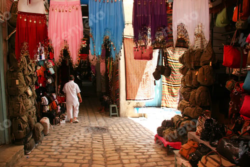 Preview: A Man Walking Through A Covered Shopping Street Covered With Merchandise Such As Clothing And Bags
