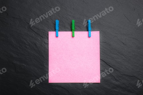 Preview: Close Up Of A Pink Note Paper And Clothes Pegs On A Black Background
