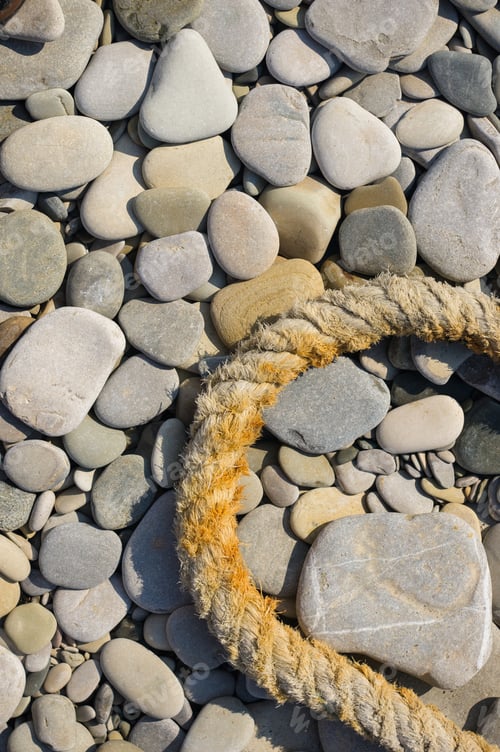 Preview: Old Worn Battered Marine Rope On The Pebble Beach On A Sunny Summer Day, Top View