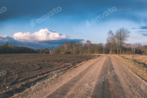 Preview: Winding Country Road With Clouds Above And Gravel Surface Surrounded By Trees - Vintage Retro Look
