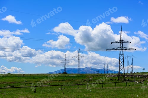 Preview: Beautiful Photograph Of A Row Of Transmission Towers And Power Lines Against A Blue Cloudy Sky