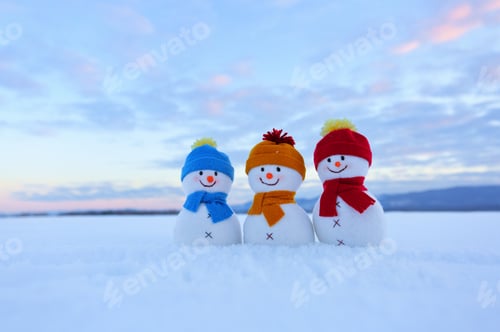Preview: Three Small Snowman In Colorful Hats Are Standing On The Snow. The Scenery With Mountains, Field In