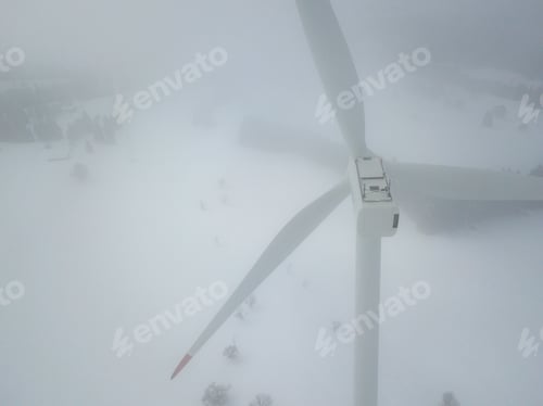 Preview: Aerial View Of Wind Turbine In Snow Covered Landscape In Switzerland. Tall Pylon In Fog, Fir Trees