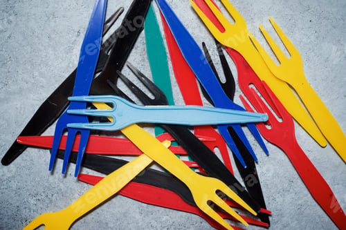 Preview: Multicolored Plastic Cutlery On A Stone Table.
