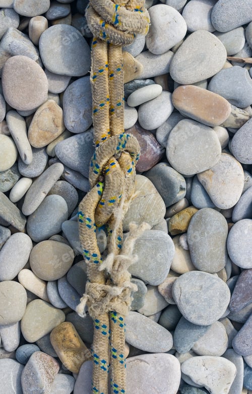 Preview: Old Worn Battered Marine Rope On The Pebble Beach On A Sunny Summer Day