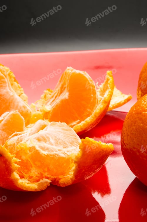 Preview: Tangerines, Peeled Tangerine And Tangerine Slices In A Red Plate On Black Background