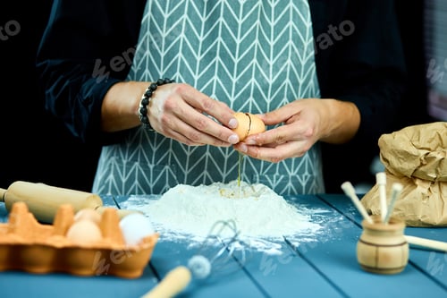 Preview: Breaking Eggs In The Flour. Close Up Of Male Hands Breaking Raw Egg Over Flour. Baker Kneading