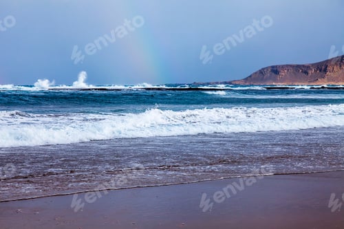 Preview: Picturesque Waves Wash The Sandy Beach On The Seashore During A Surf. A Rainbow On The Horizon