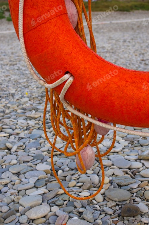 Preview: Orange Lifebuoy On A Pebbly Sea Beach, Sunset