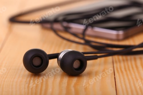 Preview: Mobile Phone With Pair Of Earphone On Wooden Table
