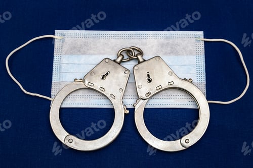 Preview: Medical Flu Mask And Handcuffs On The Blue Fabric Background Closeup