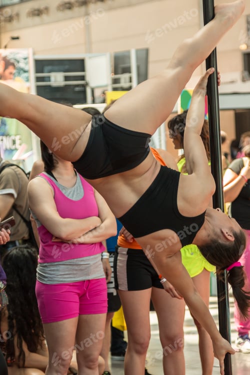 Preview: Sexy Young Woman Working Out And Practicing A Difficult Pose In Pole Fitness Class