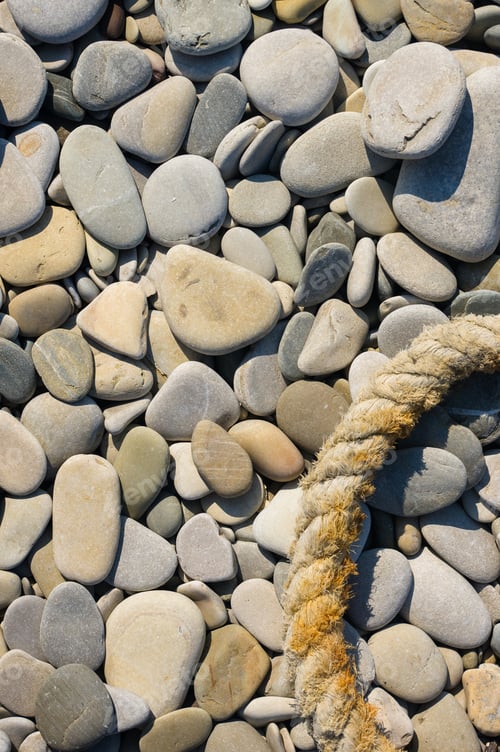 Preview: Old Worn Battered Marine Rope On The Pebble Beach On A Sunny Summer Day, Top View