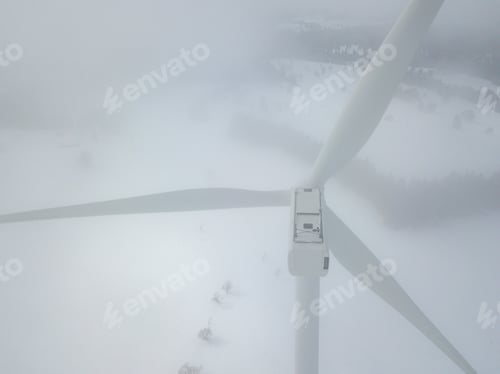 Preview: Aerial View Of Wind Turbine In Snow Covered Landscape In Swizterland. Tall Pylon In Fog, Fir Trees