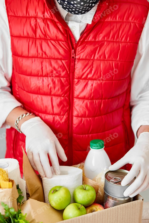 Preview: Volunteer In The Protective Medical Mask And Gloves Putting Food In Donation Box.